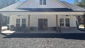 A two-story house with a covered porch, a front door, and a chimney. - Cottage near Elijah State Park, Savannah Lakes Village, Baker and Hickory Knob. (Lincolnton)
