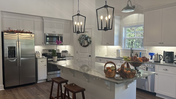 A modern kitchen with white cabinetry, stainless steel appliances, a marble island, and pendant lighting. - Cottage near Elijah State Park, Savannah Lakes Village, Baker and Hickory Knob. (Lincolnton)