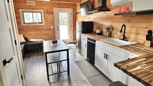 Une cuisine moderne avec des murs en bois, un coin repas et un petit chien.