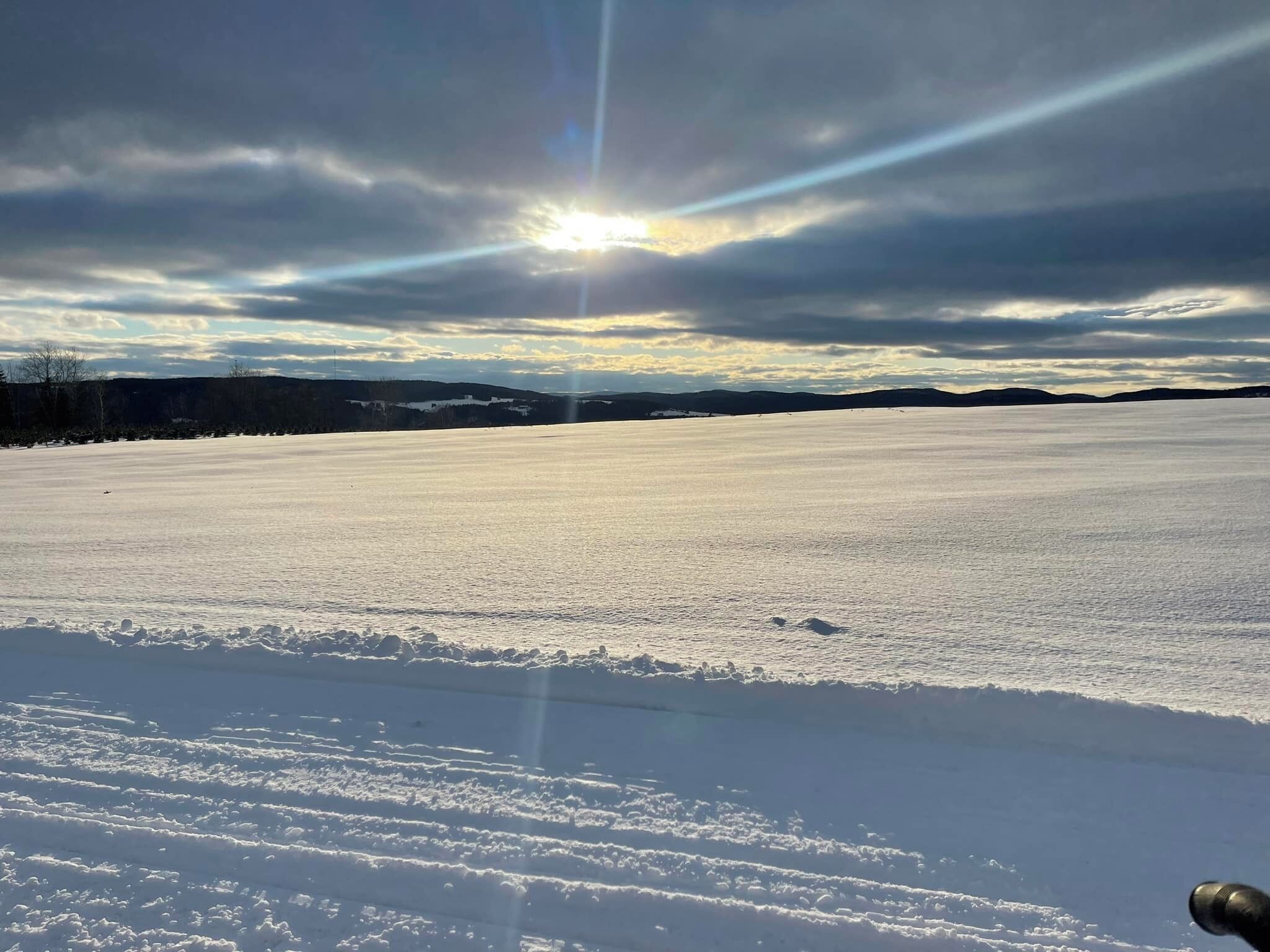 A vast, open snowy landscape with a clear sky and distant hills.