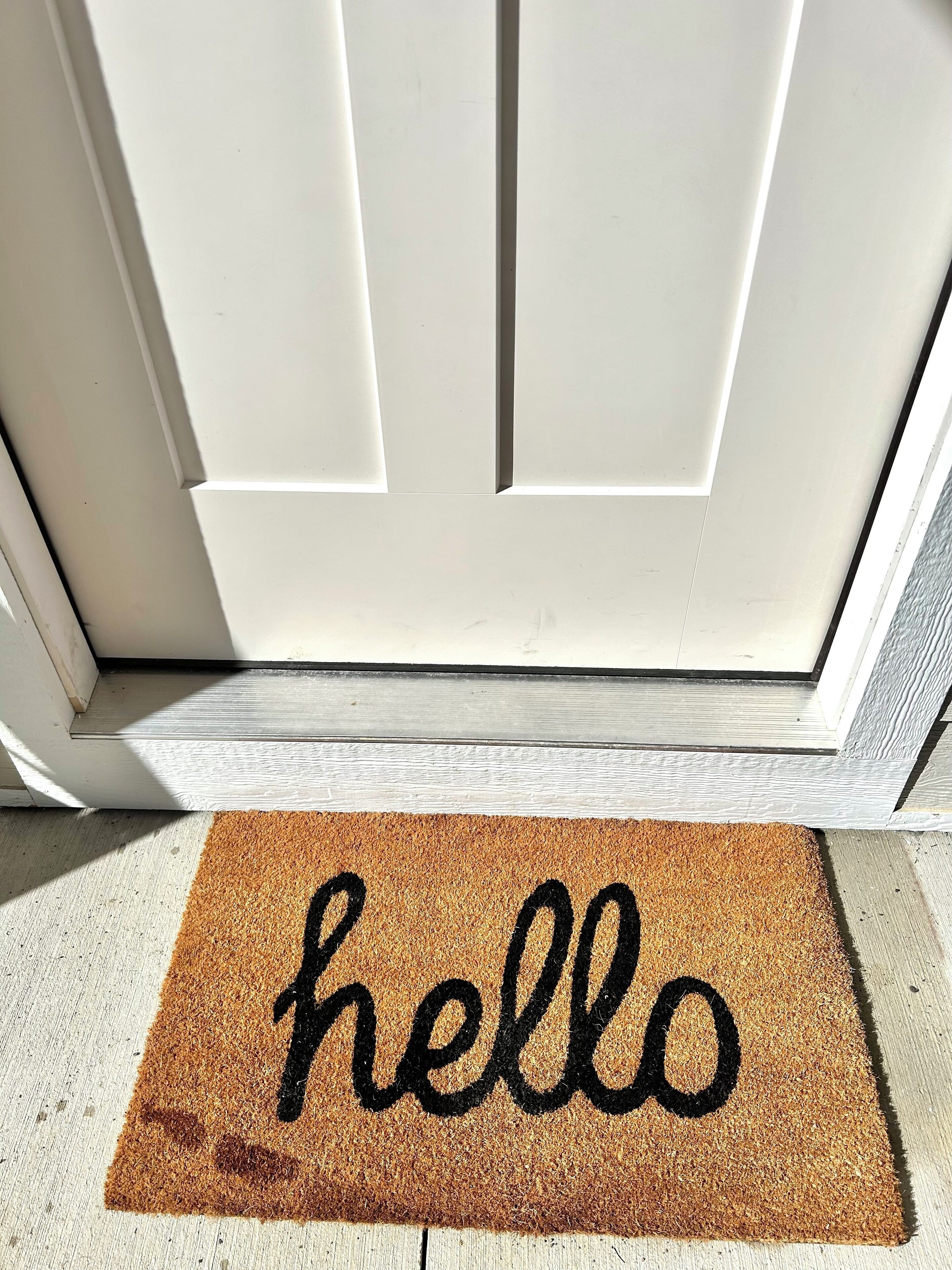 A white door with a brown doormat that reads "hello".