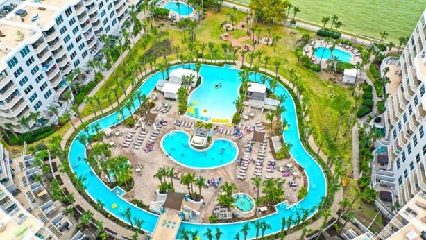 Ein Resort mit mehreren Schwimmbecken, Liegestühlen und einer begrünten, zentral gelegenen Anlage.