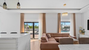 A modern living room with a sectional sofa, a marble coffee table, and a kitchen area with a marble countertop. - Villa Lukas with 4 bedrooms, a high-quality family property in the Makarska hinterland (Gornji Vinjani)
