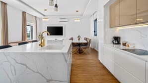 A modern kitchen with a marble island, a dining area with a table and chairs, and a TV mounted above the island. - Villa Lukas with 4 bedrooms, a high-quality family property in the Makarska hinterland (Gornji Vinjani)