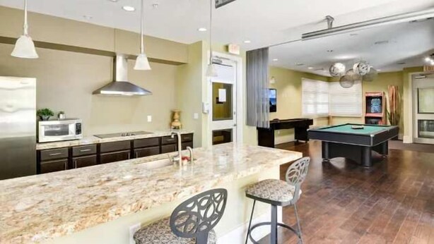 A modern kitchen with a marble island, dark cabinetry, and pendant lighting.