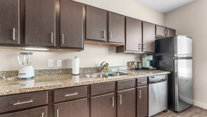 A modern kitchen with dark wood cabinets, stainless steel appliances, and a granite countertop.