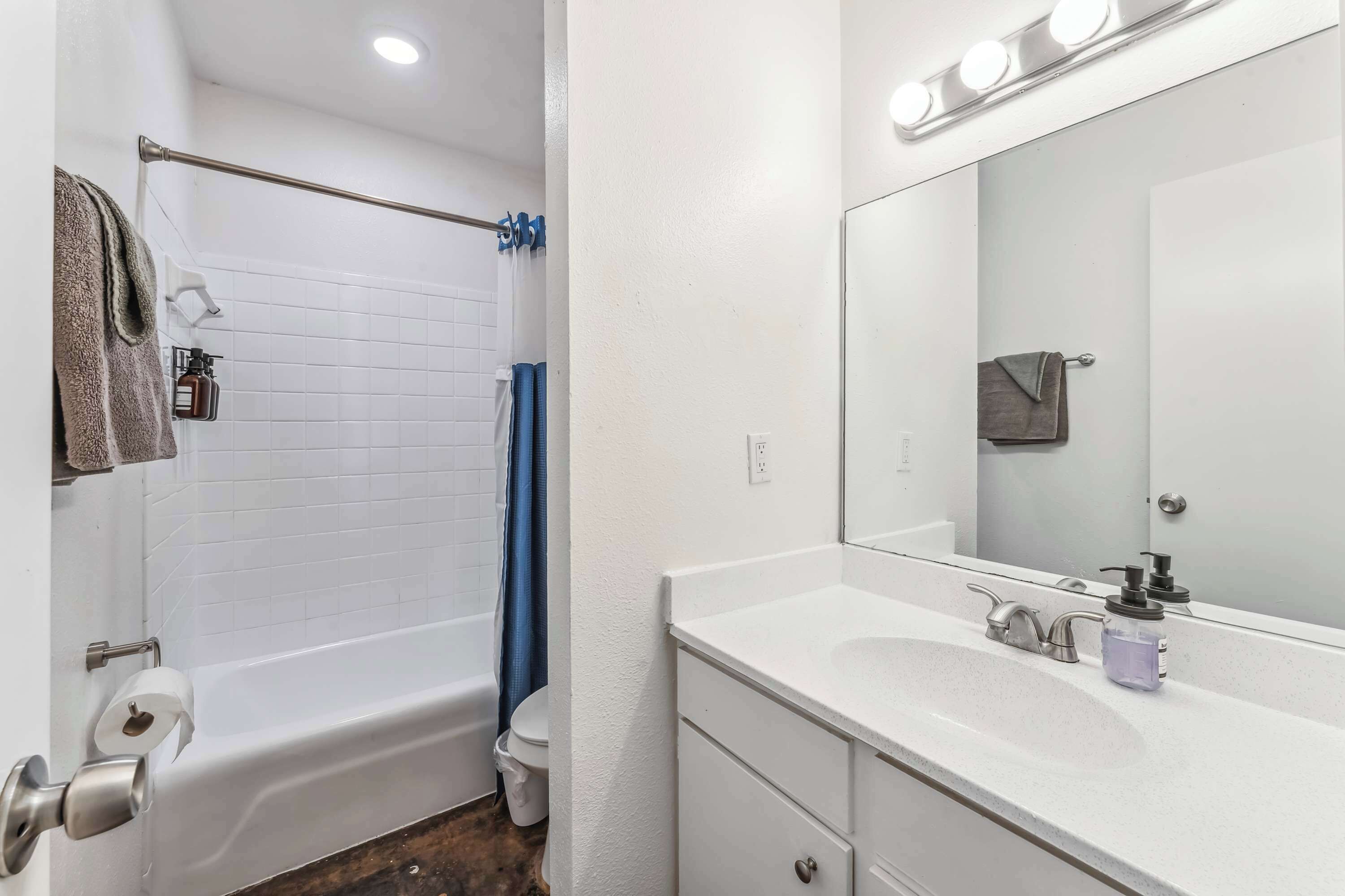 A bathroom with a white bathtub, a sink with a mirror, and a towel rack.