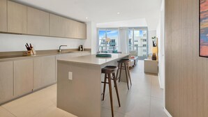 Une cuisine moderne dotée d’un îlot central, de tabourets de bar et offrant une vue sur la ville grâce à de grandes fenêtres.