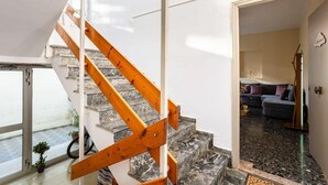 Un escalier avec des rampes en bois mène à un espace de vie comprenant un canapé et une table basse.