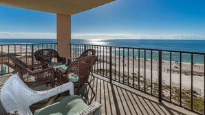 A balcony with wicker furniture and a view of the beach.