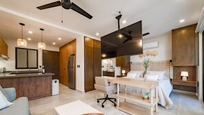 Habitació d'hotel moderna amb cuineta, zona de menjador, un llit gran i un ventilador de sostre.