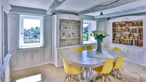 A dining area with a round table, yellow chairs, a vase with flowers, and a bookshelf filled with books. - Maison Eclaircie - Three Bedroom Villa, Sleeps 6 (Gordes)