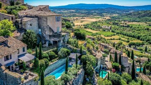 A stone building with a swimming pool, surrounded by lush greenery and a scenic view of distant hills. - Maison Eclaircie - Three Bedroom Villa, Sleeps 6 (Gordes)