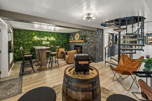 Una sala moderna con chimenea de piedra, una mesa redonda de madera, sillas de cuero y una pared verde.