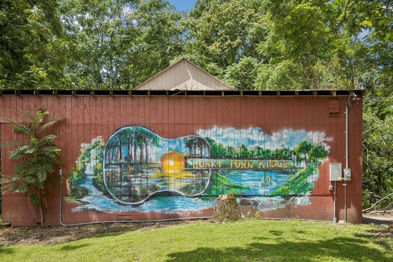 Ein Wandgemälde an einem roten Gebäude mit dem Schriftzug 'HONKY TONK RIDGE' und einer Landschaftsdarstellung.
