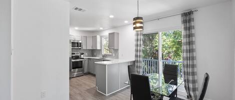 A modern kitchen with white cabinets, stainless steel appliances, and a central island.