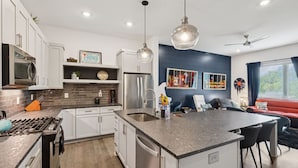 A modern kitchen with a central island, stainless steel appliances, and a dining area with a red sofa and chairs.