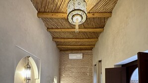 A cozy interior with a wooden ceiling, a bench, a table, and a door leading outside. - Riad Sakura Marrakech  (Marrakech)