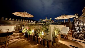 An outdoor patio area with multiple potted plants, wooden chairs, and umbrellas. - Riad Sakura Marrakech  (Marrakech)