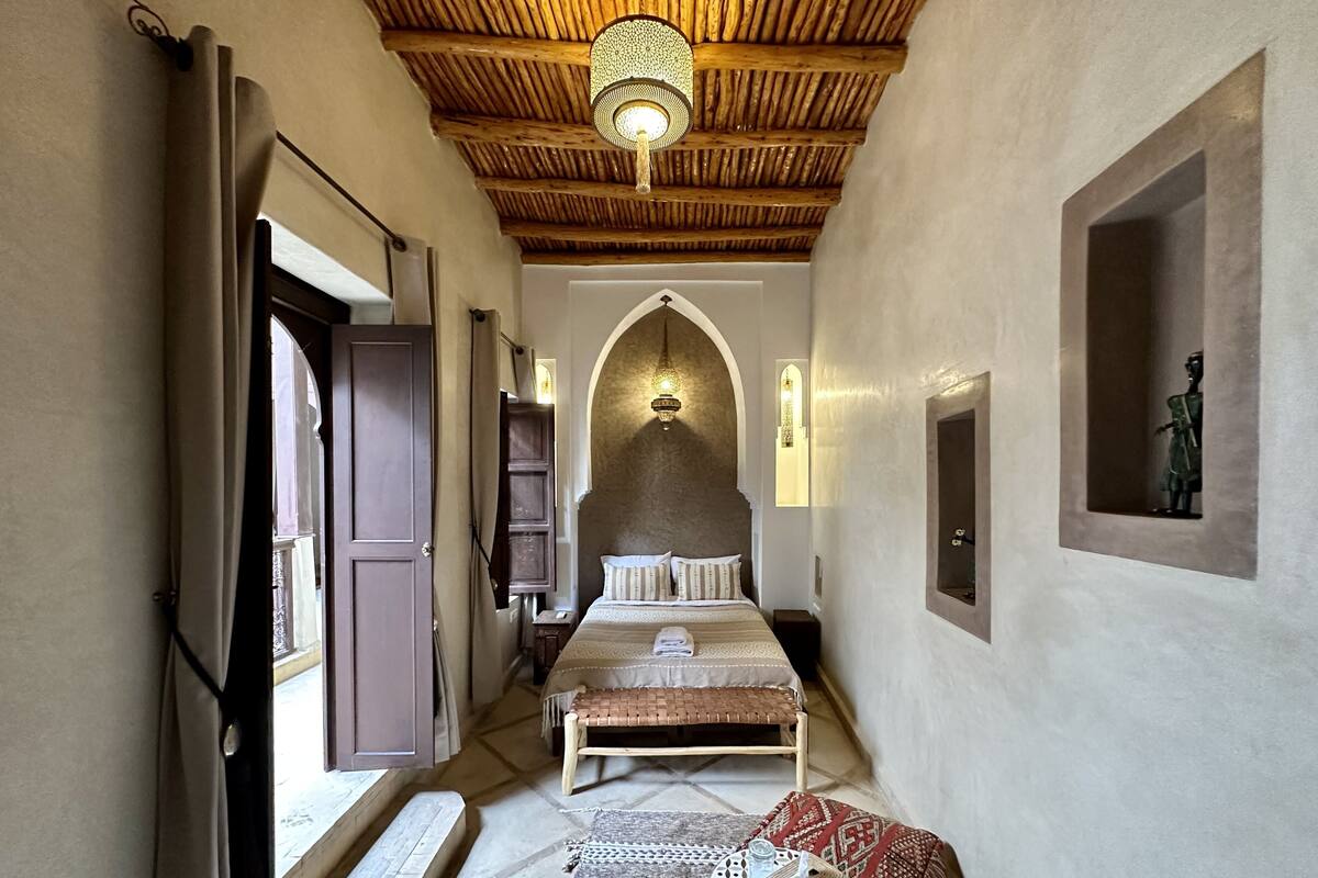 A narrow hallway with a bed, a bench, and a small table with a basket.