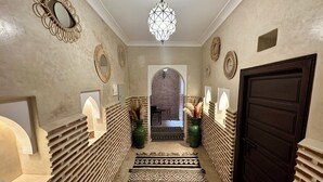 A hallway with patterned rugs, decorative mirrors, and a geometric light fixture. - Riad Sakura Marrakech  (Marrakech)