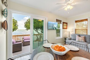 A cozy living room with a wooden table, a sofa, and a TV mounted on the wall. - ONE PARTICULAR HARBOR ~ Waterfront 2 BR/1 Ba w/ Hot Tub! (Stock Island)