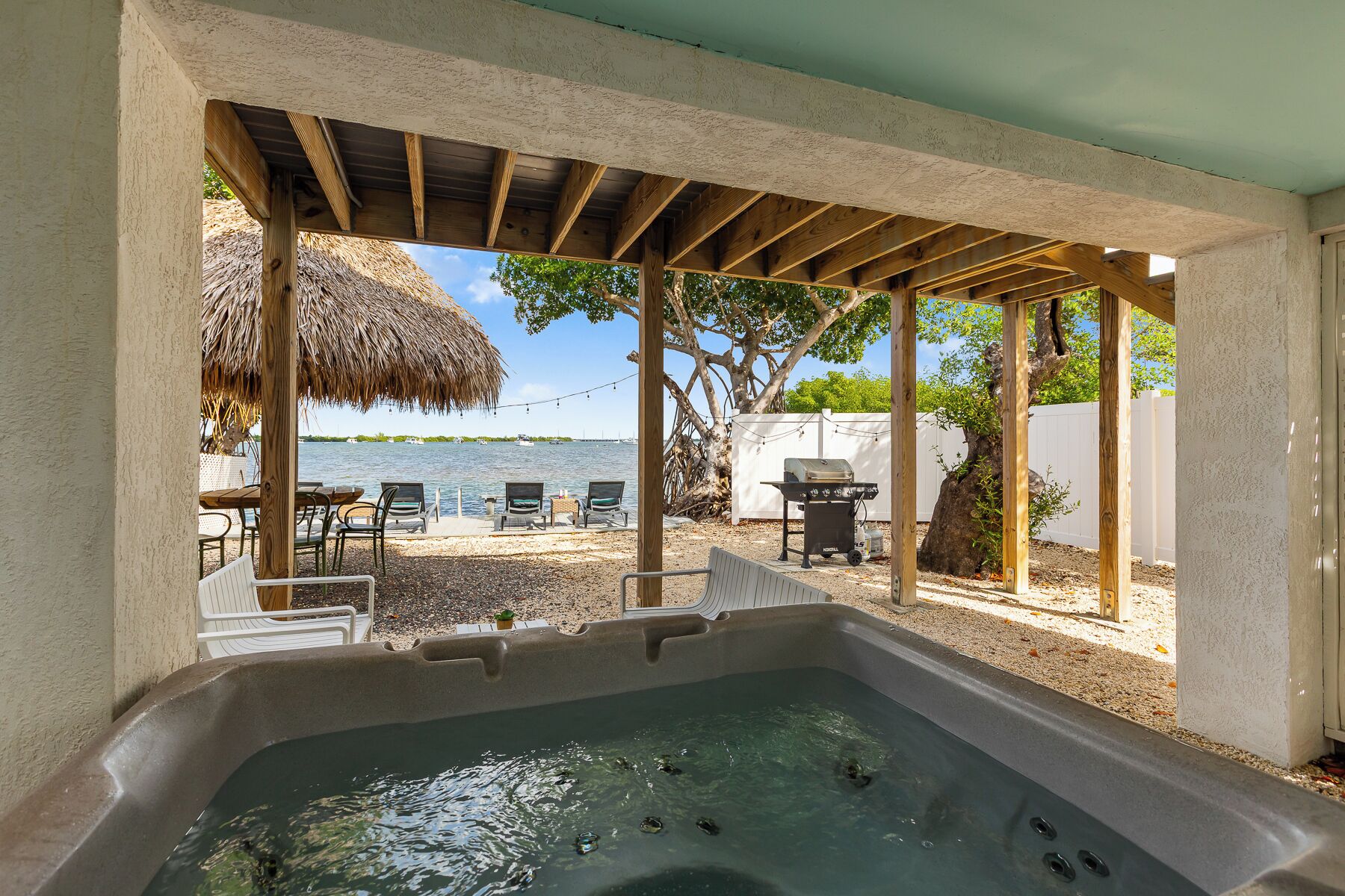 A hot tub area with a view of the sea, outdoor seating, and a barbecue grill.