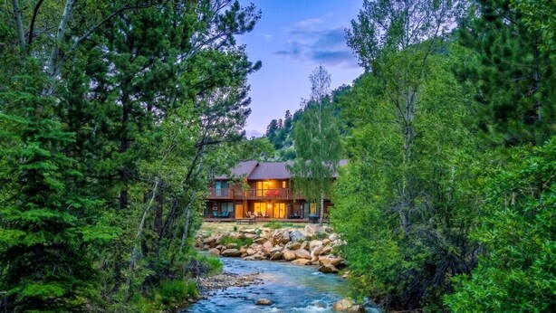 Un lodge con terrazza che si affaccia su un fiume, immerso in una fitta foresta.