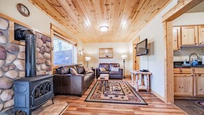 Un accogliente soggiorno con camino in pietra, soffitto in legno e angolo cottura con mobili in legno.