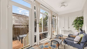 A sunlit room with a sliding glass door leading to a patio, a blue sofa, and a patterned rug.