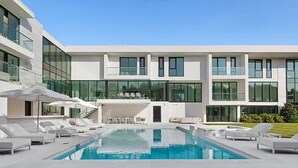 A modern building with a swimming pool, lounge chairs, and a covered seating area. - Newly developed contemporary home situated on 1.5 acres. (Water Mill)