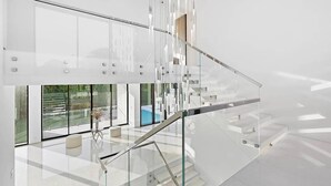 A modern interior with a glass staircase, a pool view, and a minimalist design. - Newly developed contemporary home situated on 1.5 acres. (Water Mill)