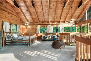 L’intérieur d’un chalet en bois, avec un lit, un canapé et un fauteuil en forme de poire.