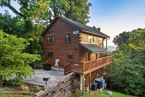 Une cabane en rondins dotée d’un balcon, entourée d’arbres.