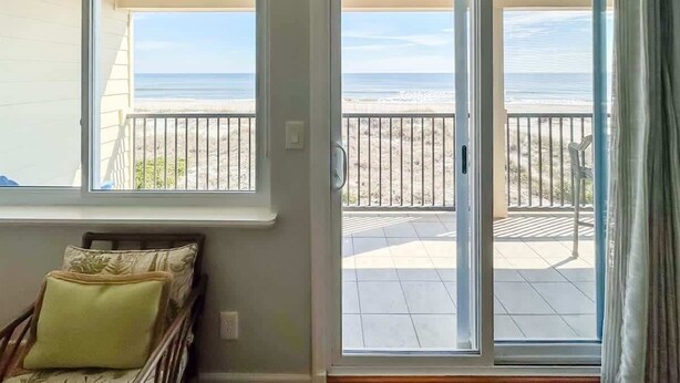 Una habitación con vista a la playa, a través de amplios ventanales y un gran ventanal corredizo.
