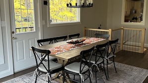 A dining area with a wooden table, black chairs, and a chandelier.