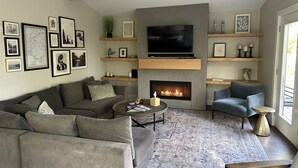 A modern living room with a fireplace, a sofa, a coffee table, and a TV.