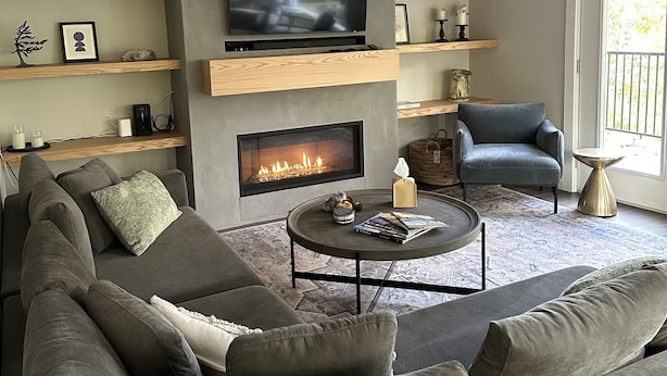 A modern living room with a large flat-screen TV, a fireplace, a sofa, and a chair.