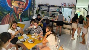 A restaurant with a mural, tables, chairs, and a bar area. - Aldeia Hostel II (Manaus)