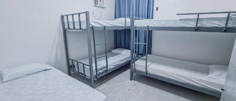 A room with bunk beds, a small table, and a wall-mounted thermostat.