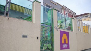 A hostel with a green gate, a purple logo, and a metal staircase. - Aldeia Hostel II (Manaus)