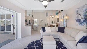 Un salon moderne avec un canapé d’angle, un coin repas et une cuisine en arrière-plan.