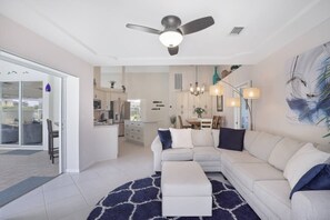 Una sala moderna con un sofá modular, un comedor y una cocina al fondo.