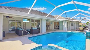 Un espace aménagé au bord de la piscine, comprenant un jacuzzi, des chaises longues et un patio couvert.