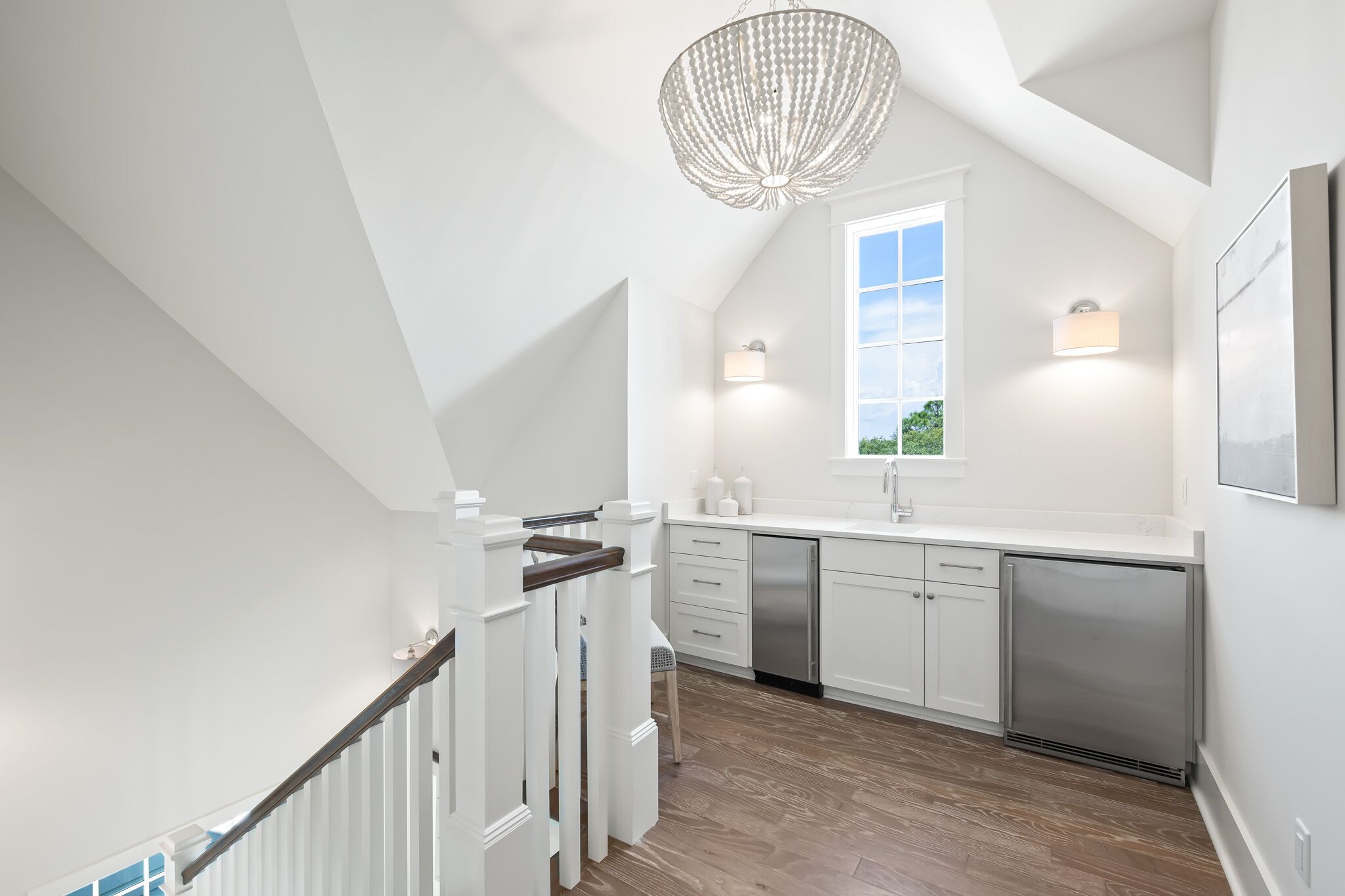 A modern kitchen with white cabinetry, stainless steel appliances, and a large window providing natural light.