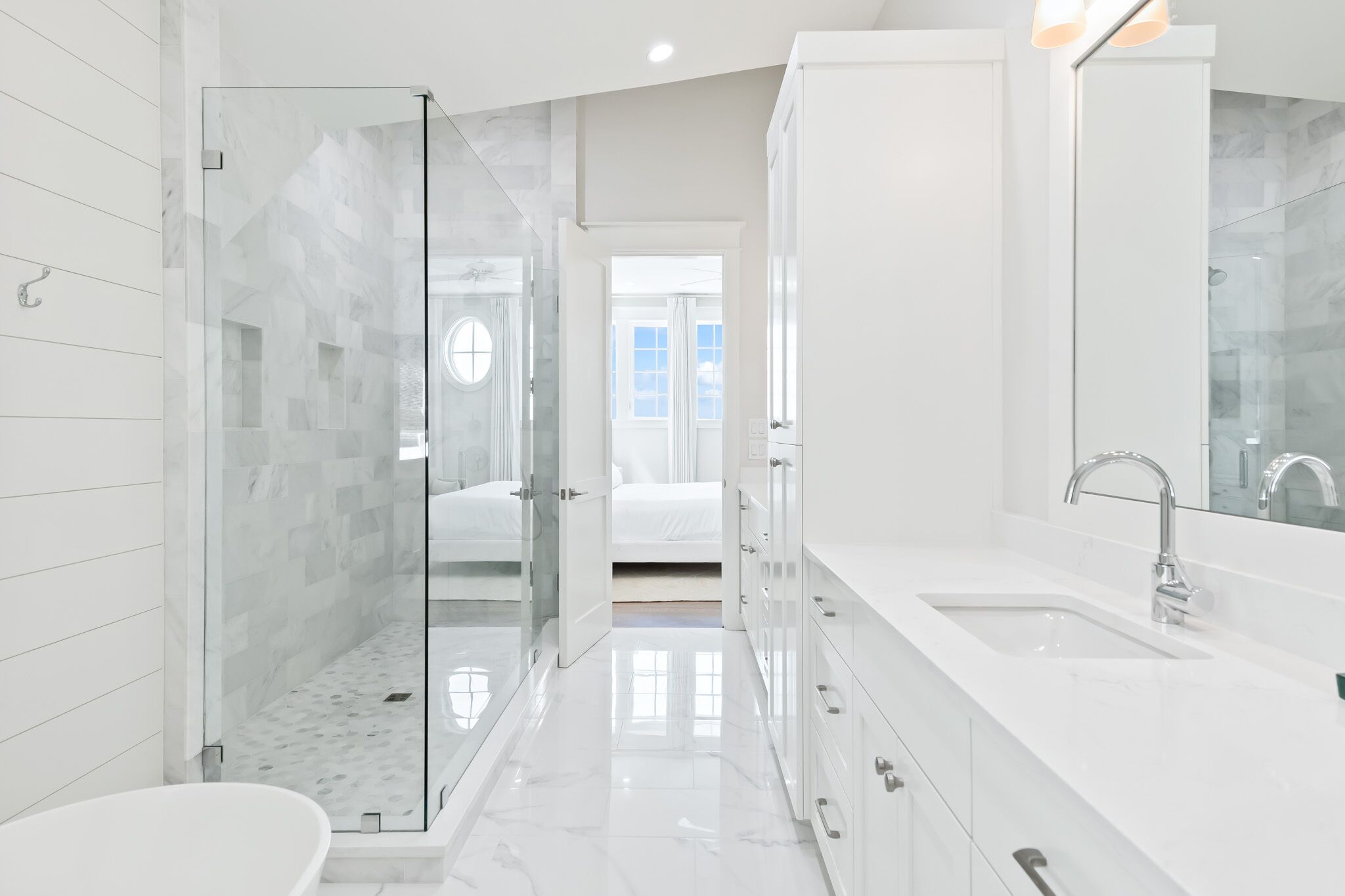 Un bagno moderno con cabina doccia in vetro, un ampio lavandino bianco e una cabina armadio.