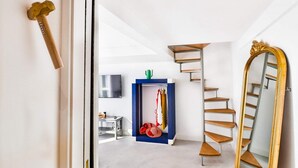 A modern interior with a spiral staircase, a large mirror, and a blue storage unit with hanging clothes. - Iommella Luxury Flat - Adami (Sant'Agnello)