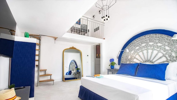 A bedroom with a large bed, a staircase, a balcony, and a decorative mirror. - Iommella Luxury Flat - Adami (Sant'Agnello)