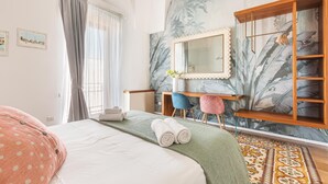 Hotellihuone, jossa on sänky, työpöytä tuolilla, peilillä varustettu meikkipöytä ja vaatekaappi.