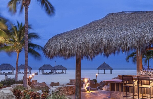 A beach resort with thatched umbrellas, palm trees, and lounge chairs. - Marriott's Crystal Shores...The Perfect Getaway in this Luxurious 2 Bedroom (Marco Island)